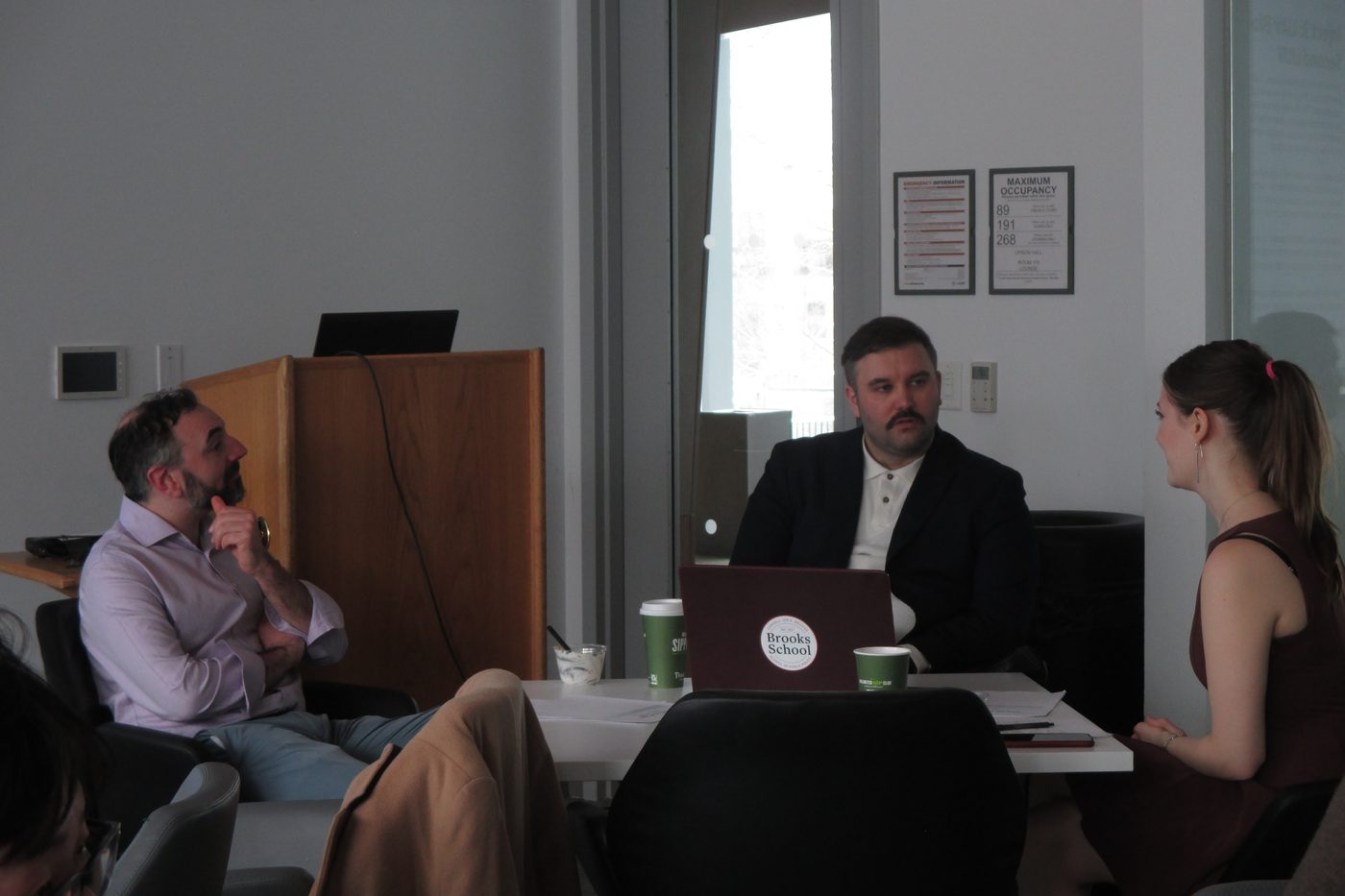 A small group in conversation around a table in the Brooks School