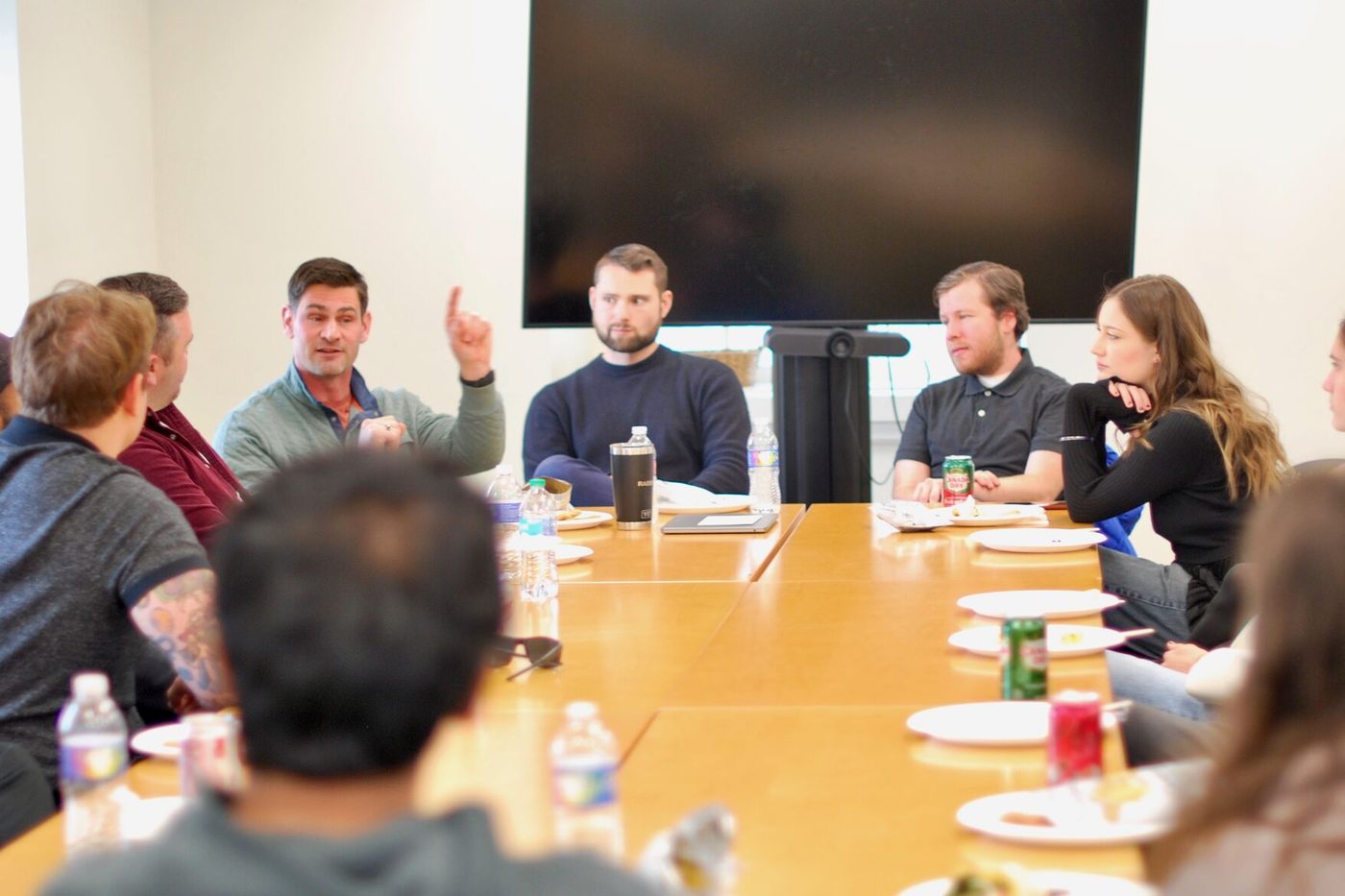 Fellows and students around a boardroom table in discussion over lunch