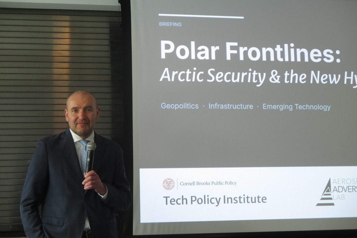 Gudni Th. Johannesson speaking with a microphone beside a slide reading Polar Frontlines, Arctic Security and the New Hybrid