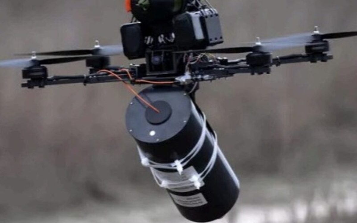 A drone carrying a payload over open ground