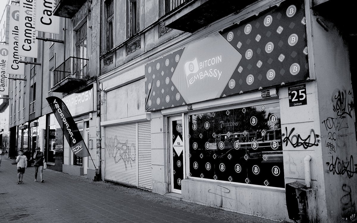 A Bitcoin Embassy shopfront on a street in Lodz, Poland, with passers-by