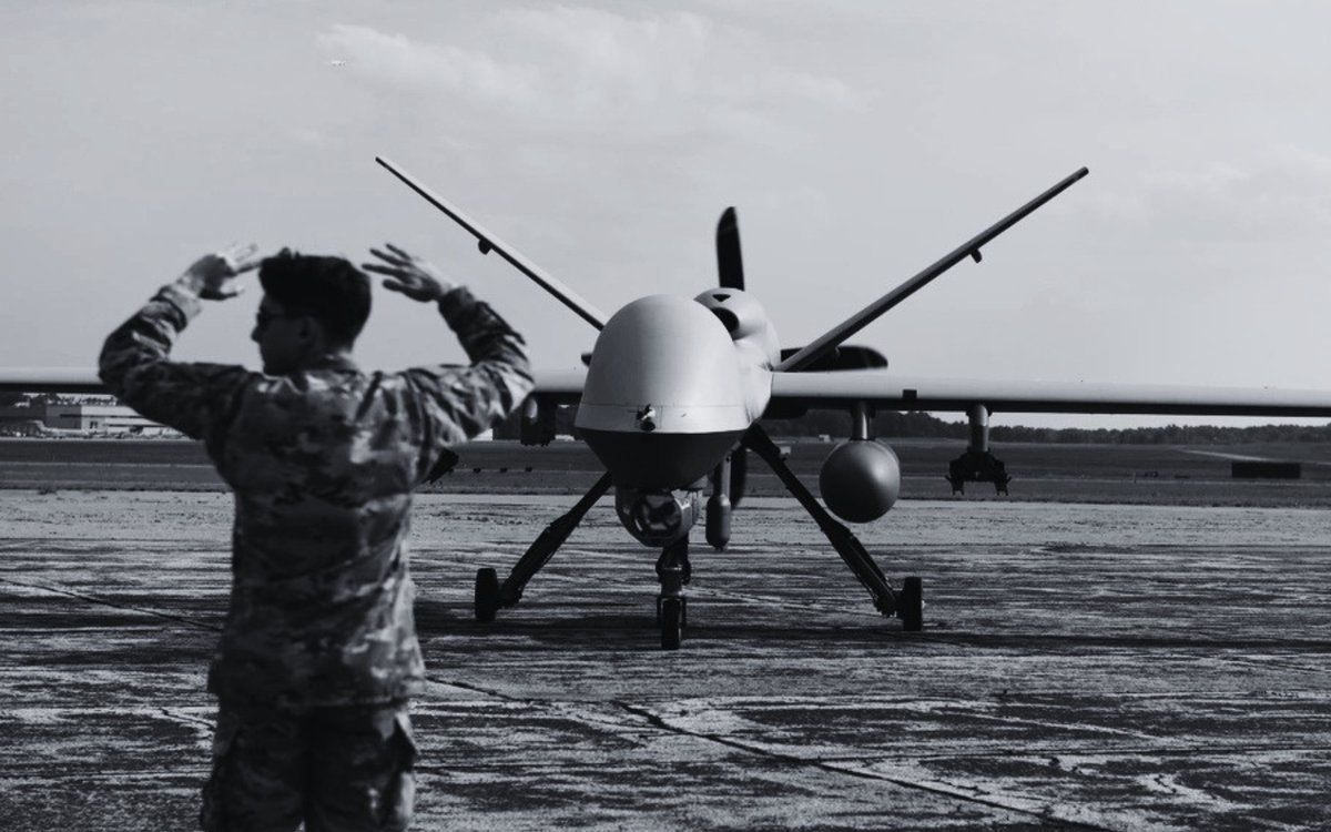 An airman marshalling an MQ-9 Reaper on an airfield apron