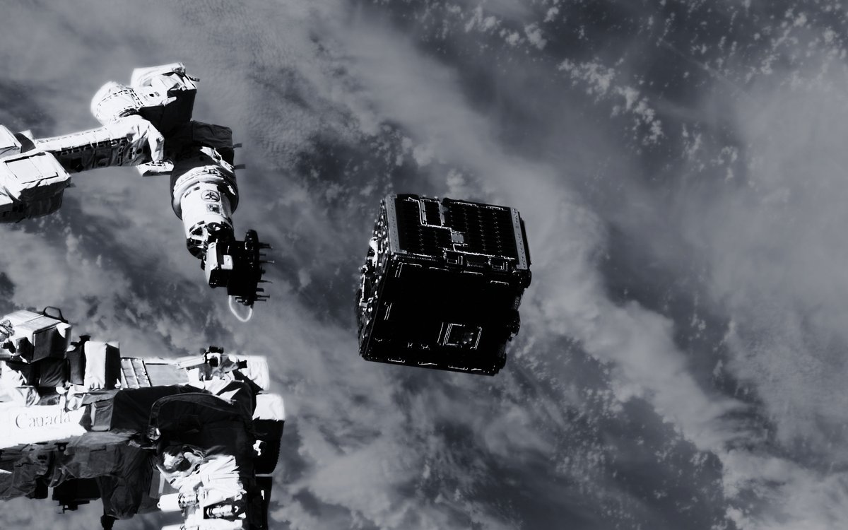 A small satellite released from a robotic arm above the Earth